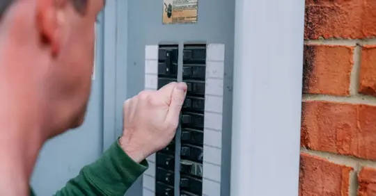 man adjusting circuit breaker